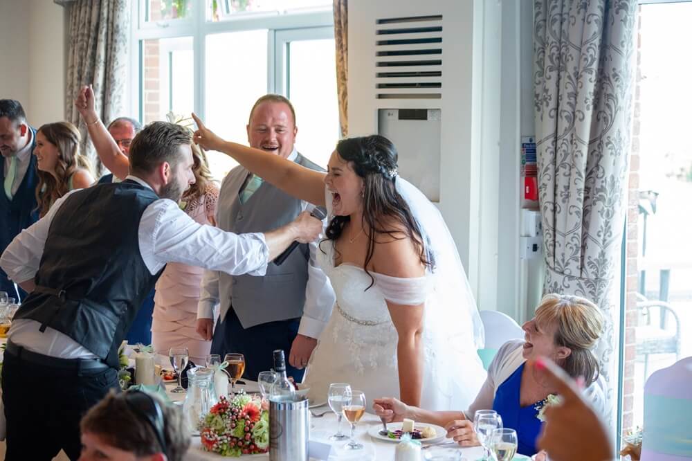 A Bride singing into the microphone with one of our singing waiters.