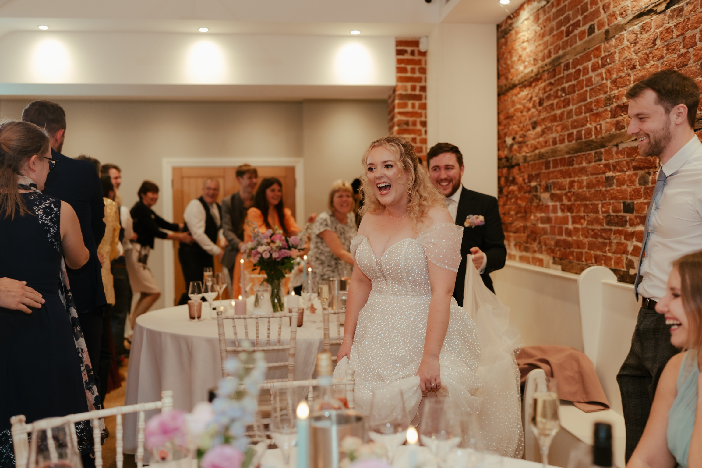 A bride laughing at the Silver Service Singers performing a conga line with her guests.